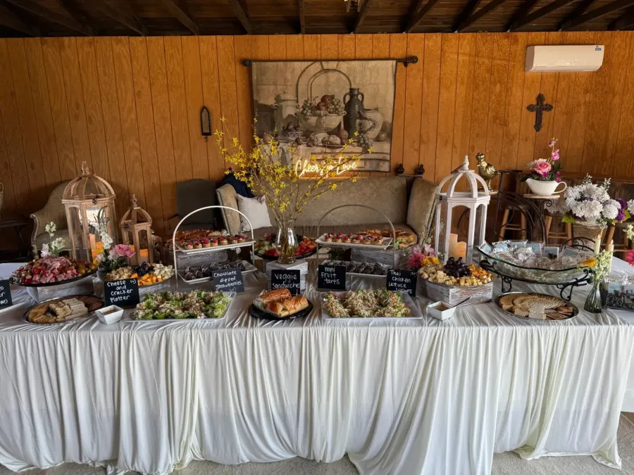 Grazing table where fresh blooms are tucked between tea sandwiches, cured meats, fruit tarts and chilled salads — floral-styled grazing for Los Altos catering