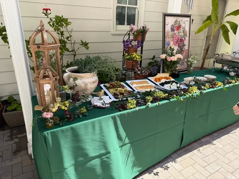 San Jose private-party catering table with generous charcuterie offerings, grape garlands, floral details, and coordinated green linens.